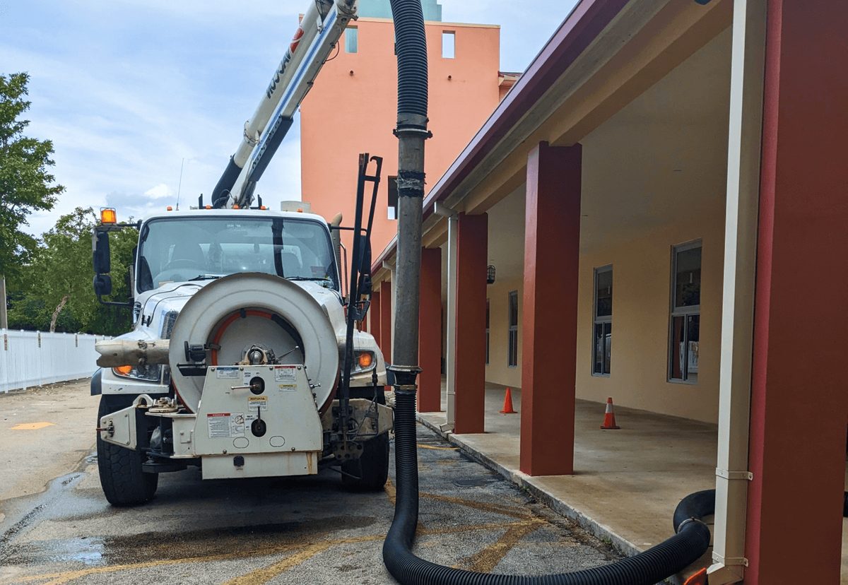 Vacuum truck with a hose beside a building for stormwater maintenance