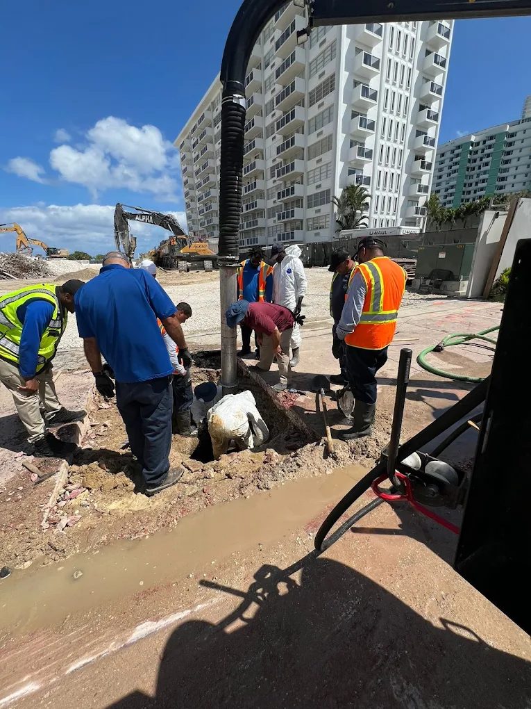 Crew exposing underground utilities in an excavation beside a building